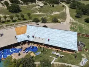 Sandstone-colored snap lock metal roof panels being installed in Texas