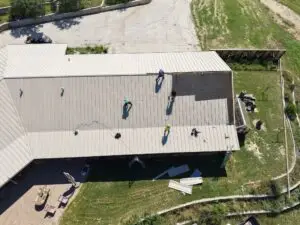 Sandstone-colored snap lock metal roof panels being installed in Texas