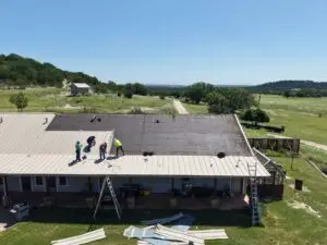 Sandstone-colored snap lock metal roof panels being installed in Texas