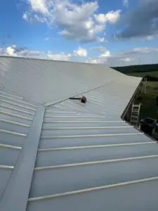 Sandstone-colored snap lock metal roof panels being installed in Texas