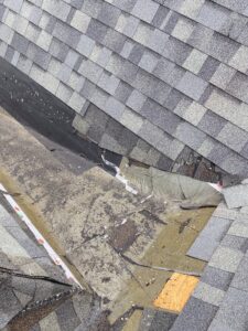 Close-up of low-slope shingle roof intersection where leak originated due to improper installation